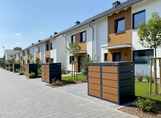 Ein Hausbesitzer begutachtet draußen eine Mülltonnenbox in Holzoptik.