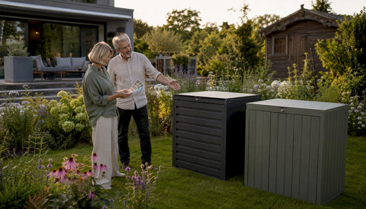 Ein älteres Ehepaar begutachtet verschiedene Mülltonnenboxen im eigenen Garten und vergleicht deren Vorteile.